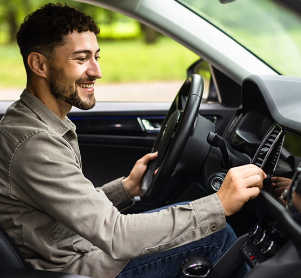 Man turning knob on navigation system 
driving with confidence knowing his car loan has guaranteed asset protection