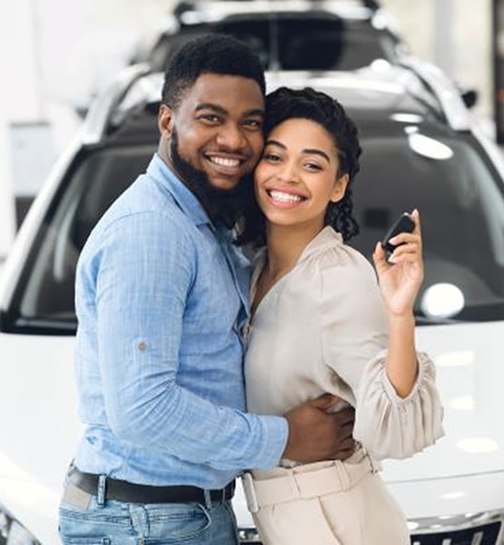 couple in front of a new car holding keys.