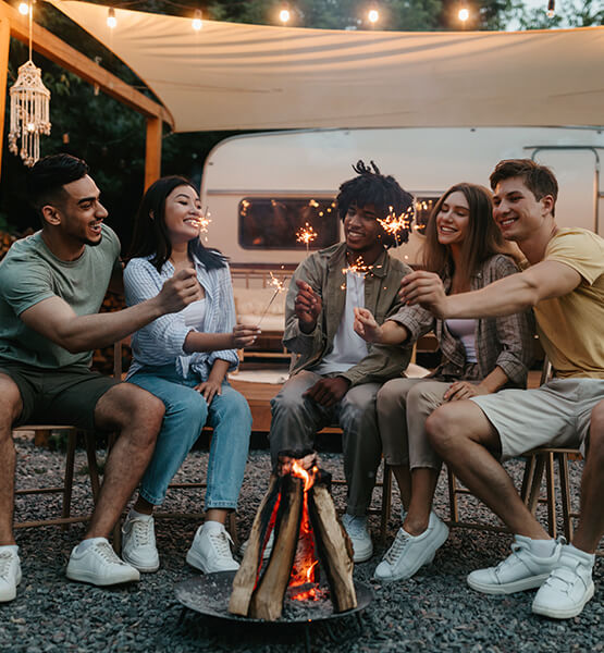 Friends gather around firepit outside of the RV