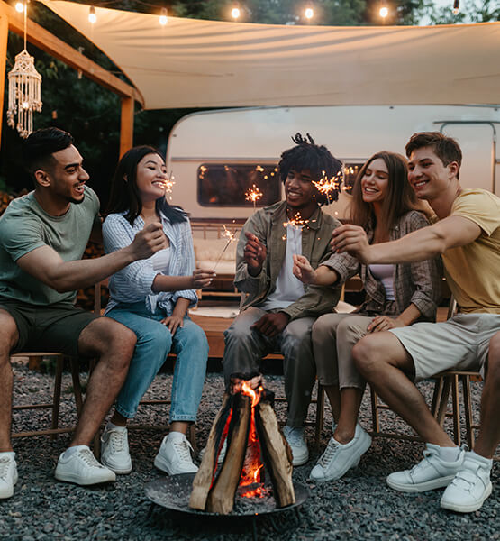 Friends gather around firepit outside of the RV