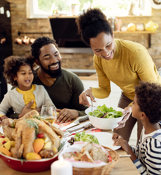 Family of four gather together at dinner table for a meal to celebrate the holidays at home