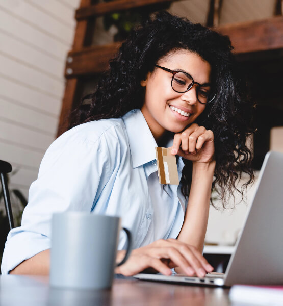 Lady holding credit card and looking at laptop screen.