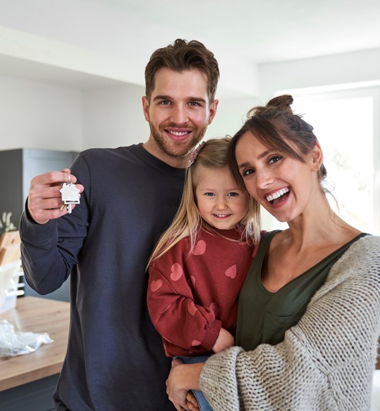 Happy couple with their child holding key to new house.