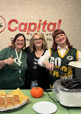 Capital Credit Union staff pose in Packers gear while preparing food for member home game tailgaters