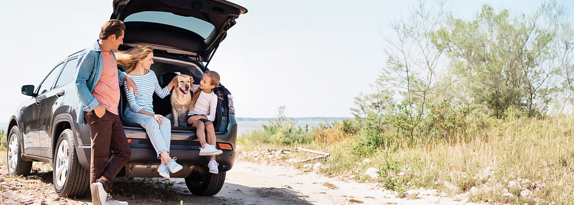 Happy family sitting in trunk of new vehicle.