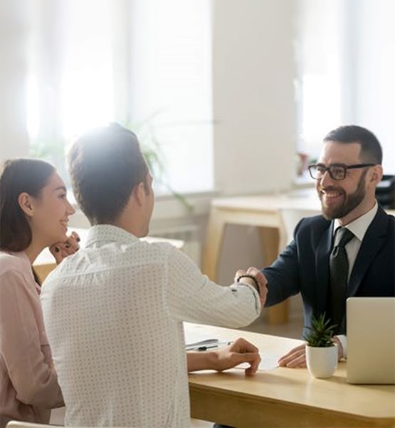 couple shaking hands with a man in suit. 