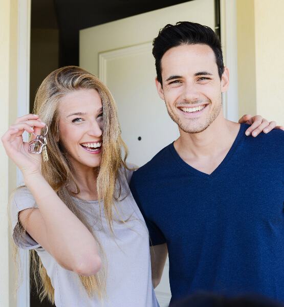 Couple smiling, holding keys to new home.