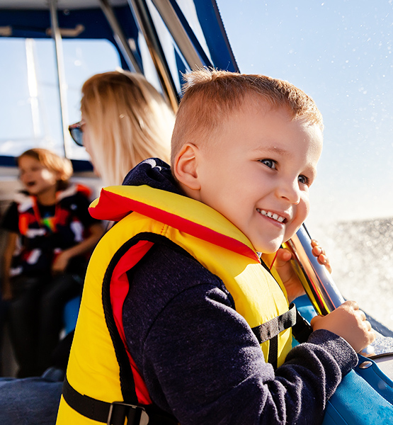 Child enjoys a recreational family boat ride alongside mother and sibling