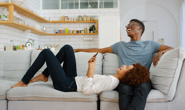 Happy couple sitting on a couch in their home. 