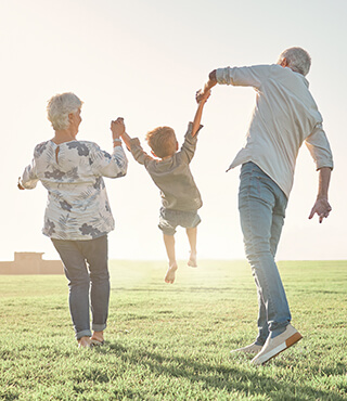 retired couple holding grandkid's hand.