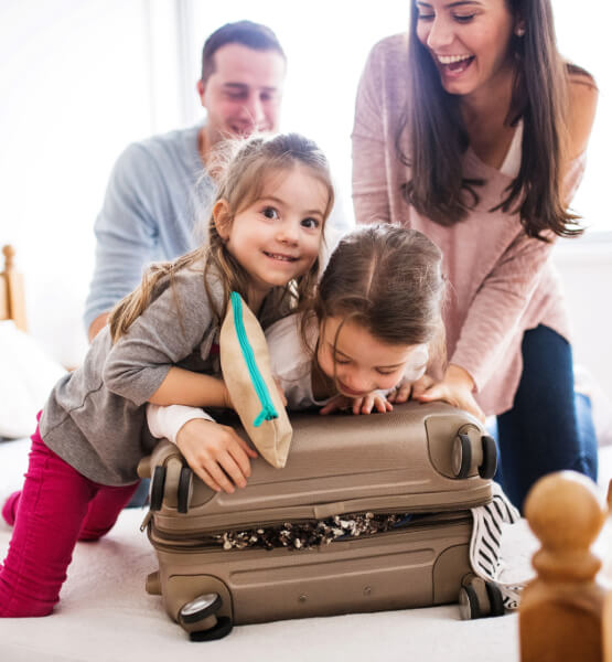 family on vacation trying to zip a overpacked suitcase.