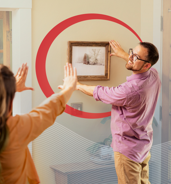couple moving into new home hanging up picture frame.