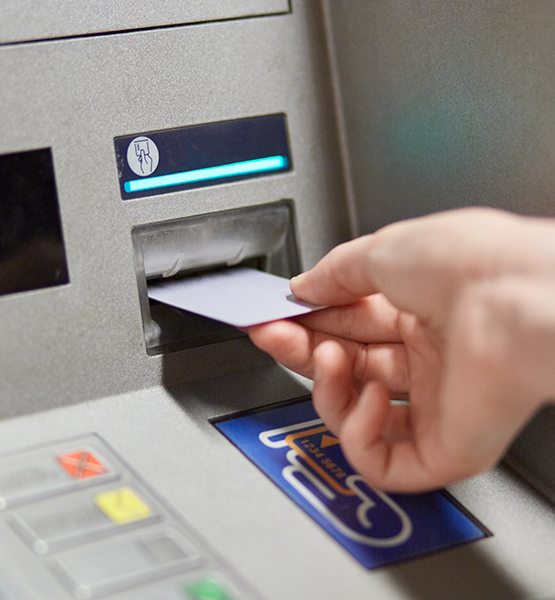 An image of someone putting a debit card into an ATM.