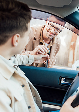 Father hands car keys to his son from outside the vehicle through the open driver side window