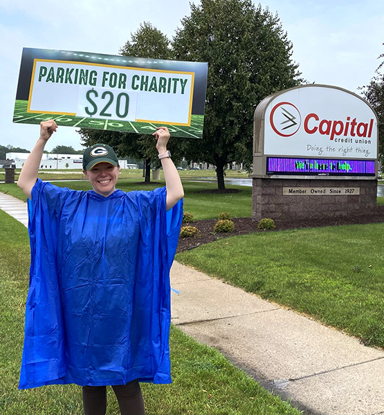 Capital Credit Union staff with sign about $20 parking for charities on Packers football home games