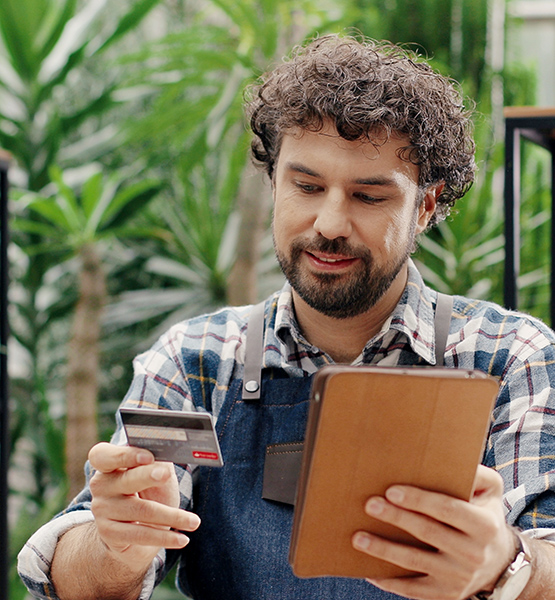 Make business owner looks at a business credit card while making a purchase over a mobile device