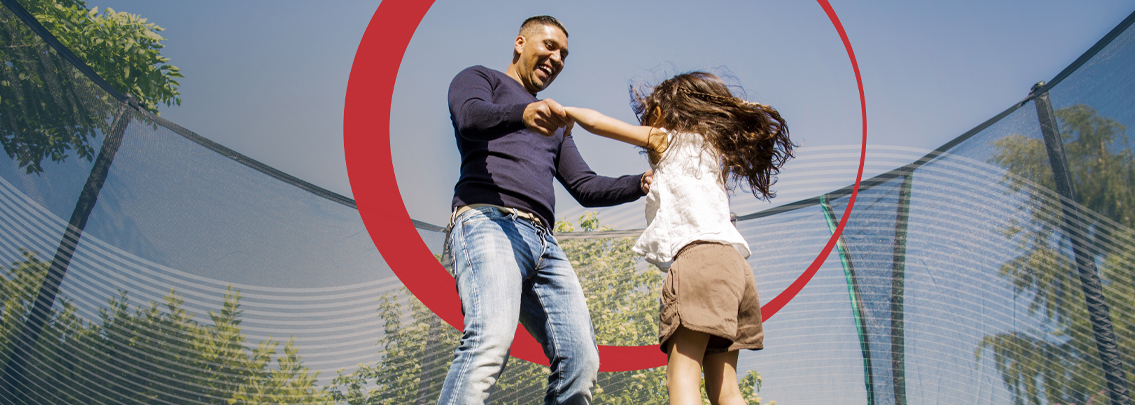 Father and daughter jumping on trampoline. 