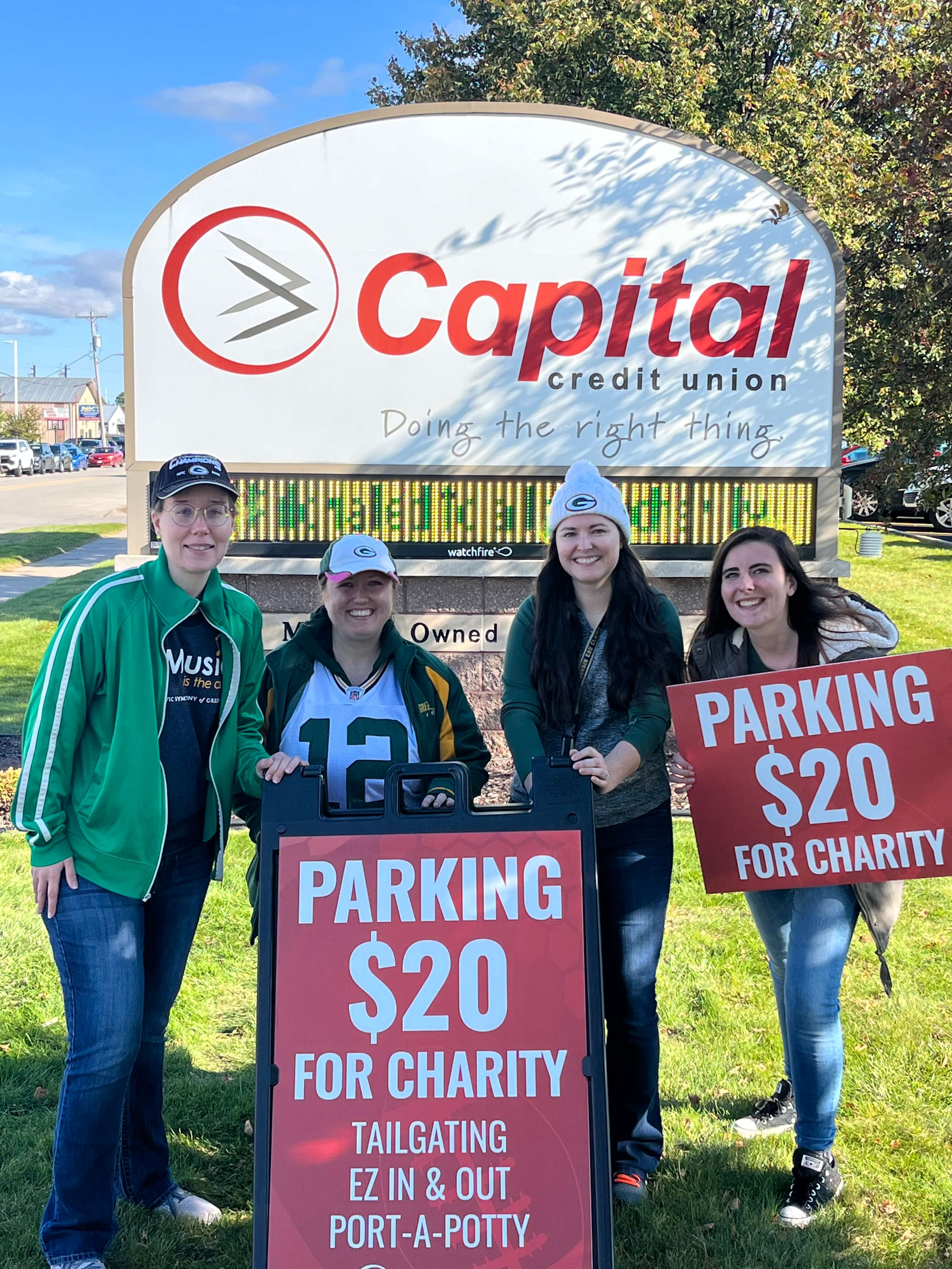 Capital employees holding parking for charity sign.