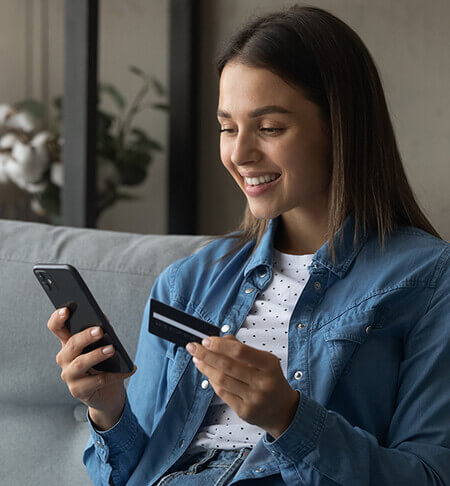 Young lady holding credit card and phone.