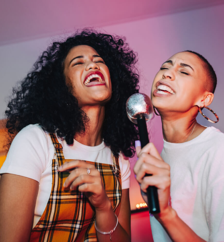 Girls smiling and singing into a microphone