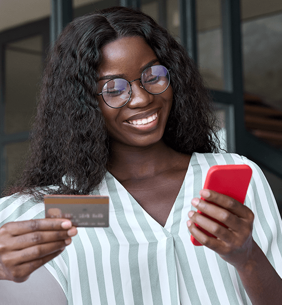 Lady in glasses holding credit card and looking browsing digital banking app her phone