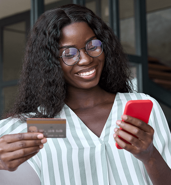 Lady in glasses holding credit card and looking browsing digital banking app her phone 