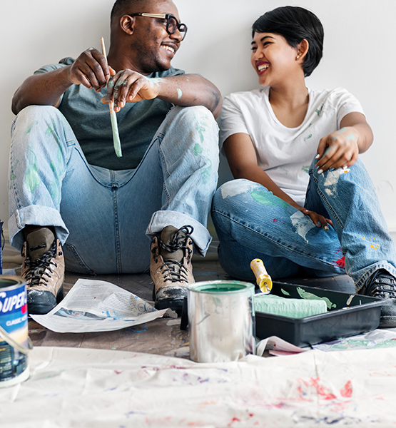Middle aged man and woman sitting and laughing together while painting and making home improvements