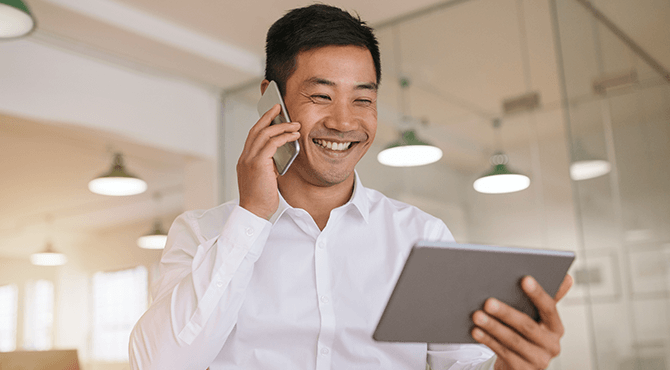 man holding tablet and on the phone.