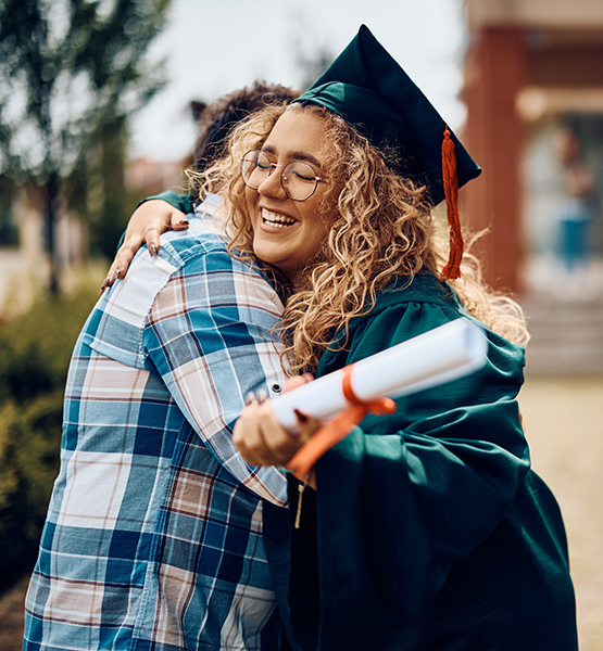 Proud father hugs his smiling daughter on her high school graduation day