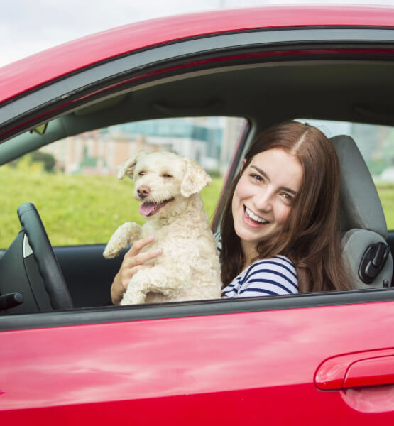 A woman and her dog in a red car. 