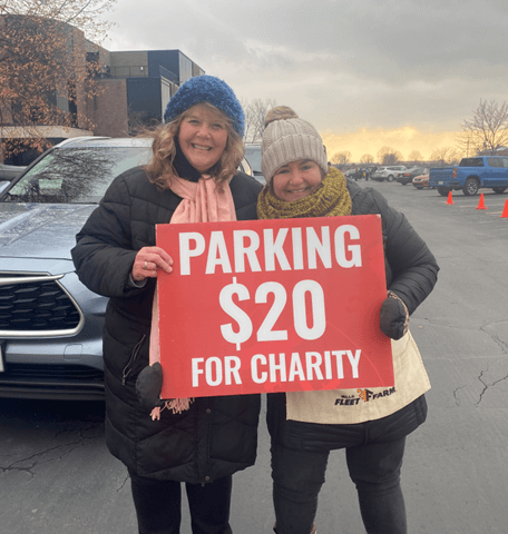 Capital employees holding parking for charity sign.