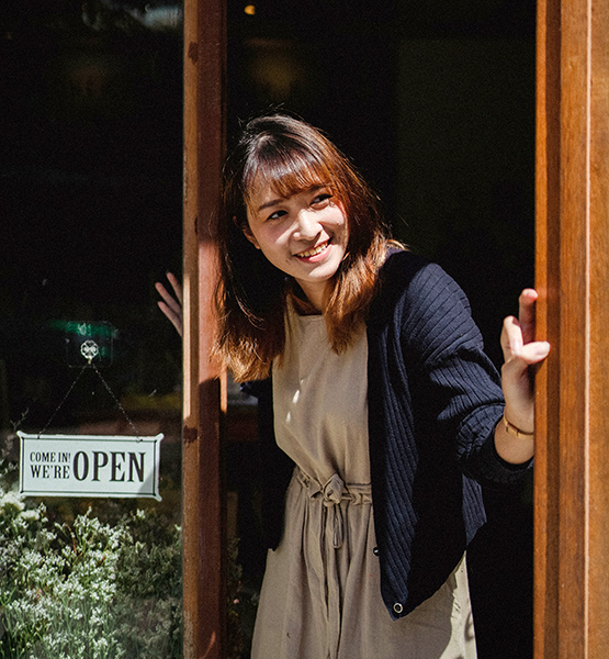 Middle aged female business owner opening door to her shop