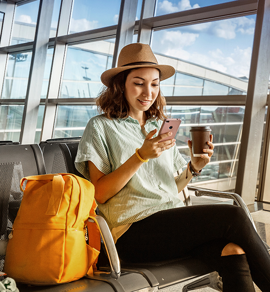 Young woman at airport confidently uses cellphone to report lost or stolen credit card while on trip