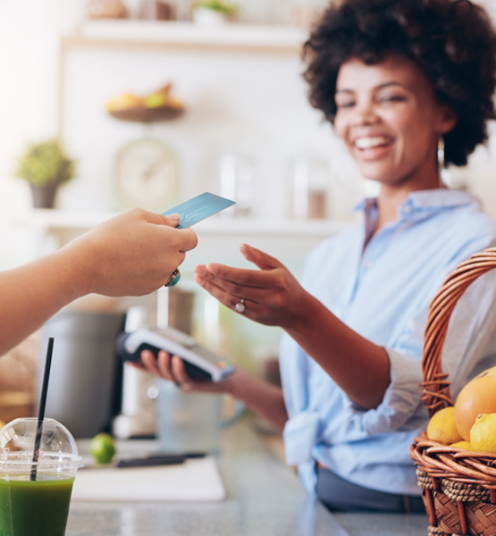 Person handing cashier their credit card, using touch to pay.