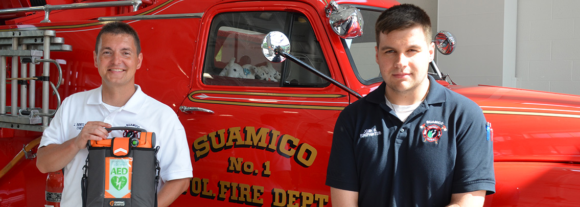 Suamico Fire Department staff pose with AED device in front of fire truck