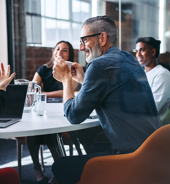 Diverse team of coworkers have a meeting around a table discussing projects over coffee