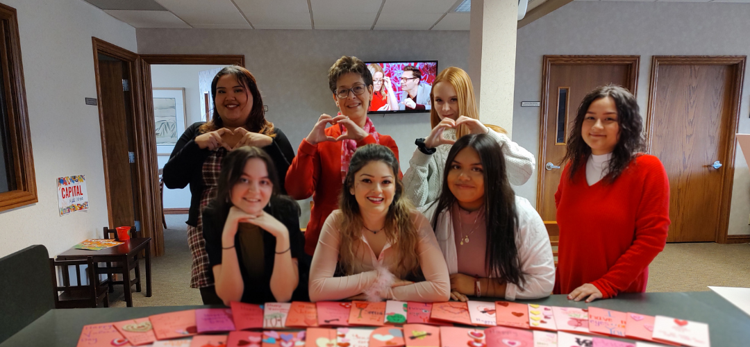 An image of women standing around a table of homemade Valentine's Day cards.