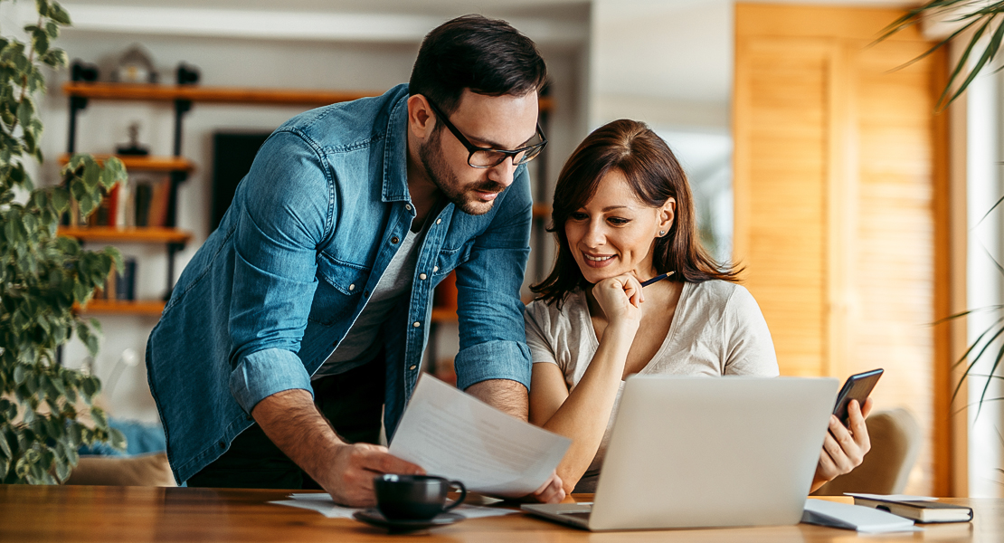 Couple looking at sheet and laptop.