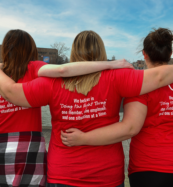 Three of Capital Credit Union's staff wear t-shirts displaying the credit union's mission statement