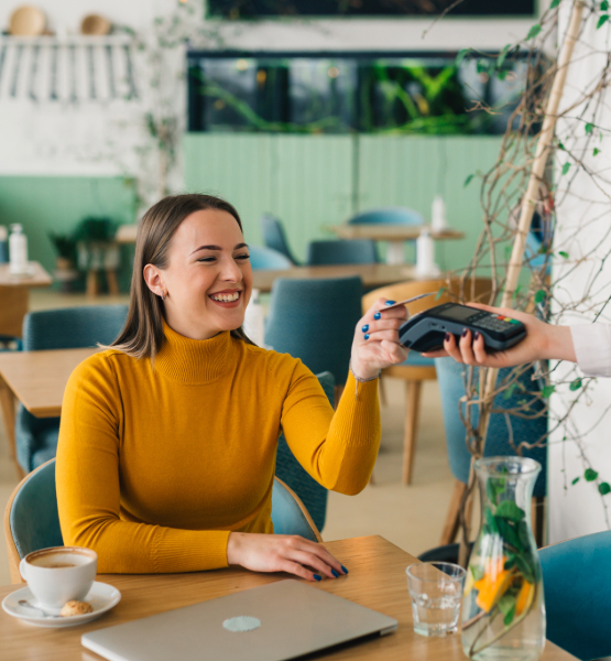 Lady using tap to pay at a cafe using her Capital Credit Union debit card.
