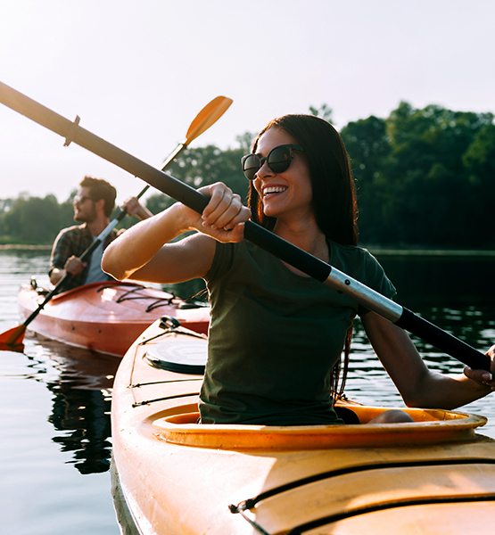 Middle aged man and woman enjoying the outdoors paddling kayaks on a lake together
